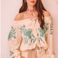Modelo con blusa boho bordada BOHEMIAN en color vainilla, con escote barco y bordado en color agua