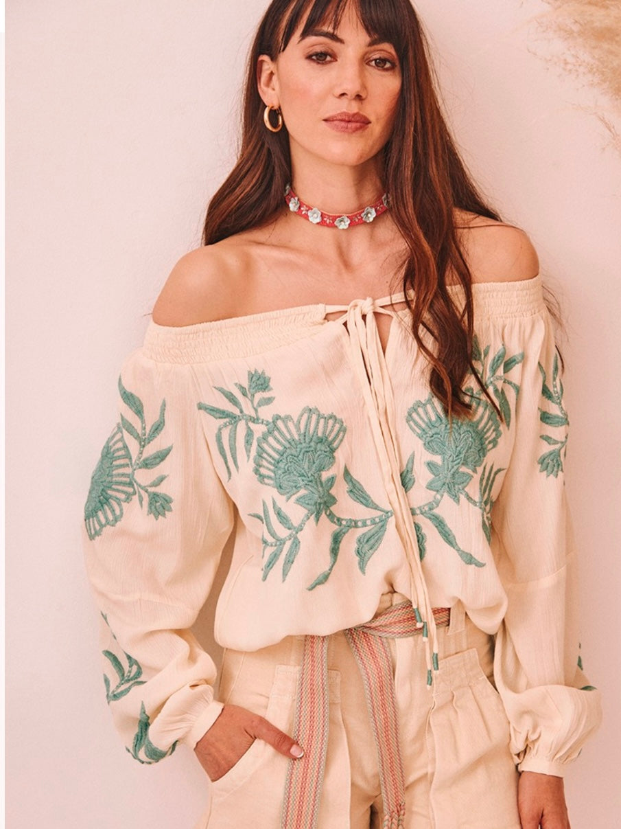 Modelo con blusa boho bordada BOHEMIAN en color vainilla, con escote barco y bordado en color agua